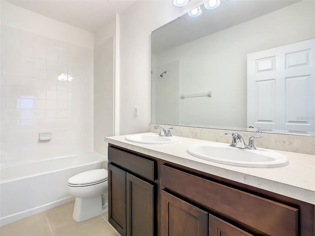 1761 Tree Shade Drive Davenport, FL 33837 - Photo 18 of 20 a bathroom with a granite countertop sink a toilet and a bathtub