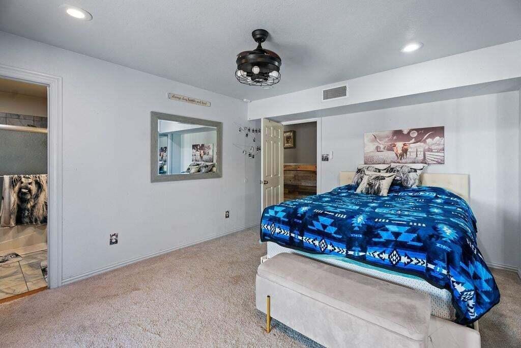 98 South Lakeshore Drive Ransom Canyon, TX 79366 - Photo 37 of 99 a bedroom with a large bed and a chandelier