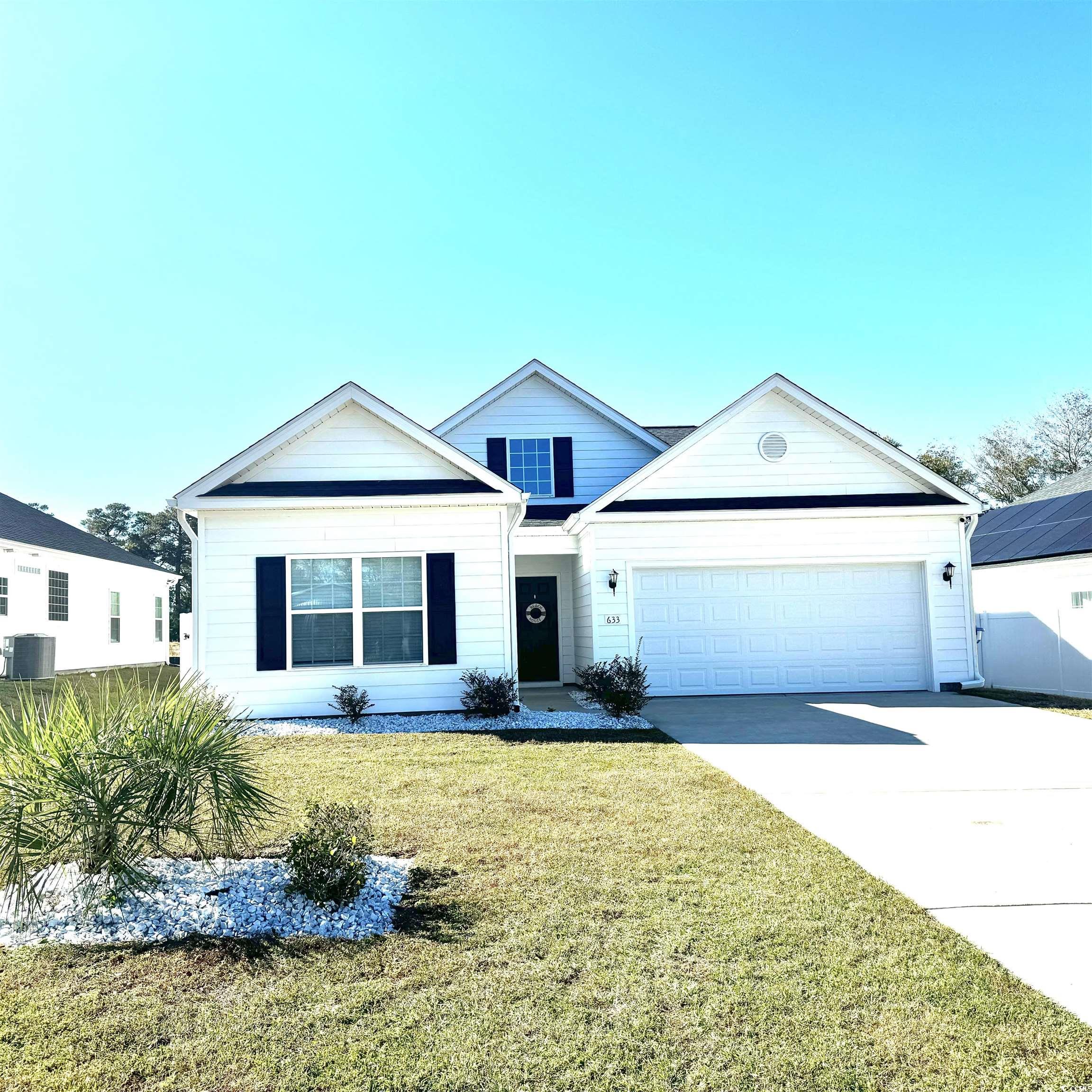 View of front of property with driveway, a front lawn, and a garage