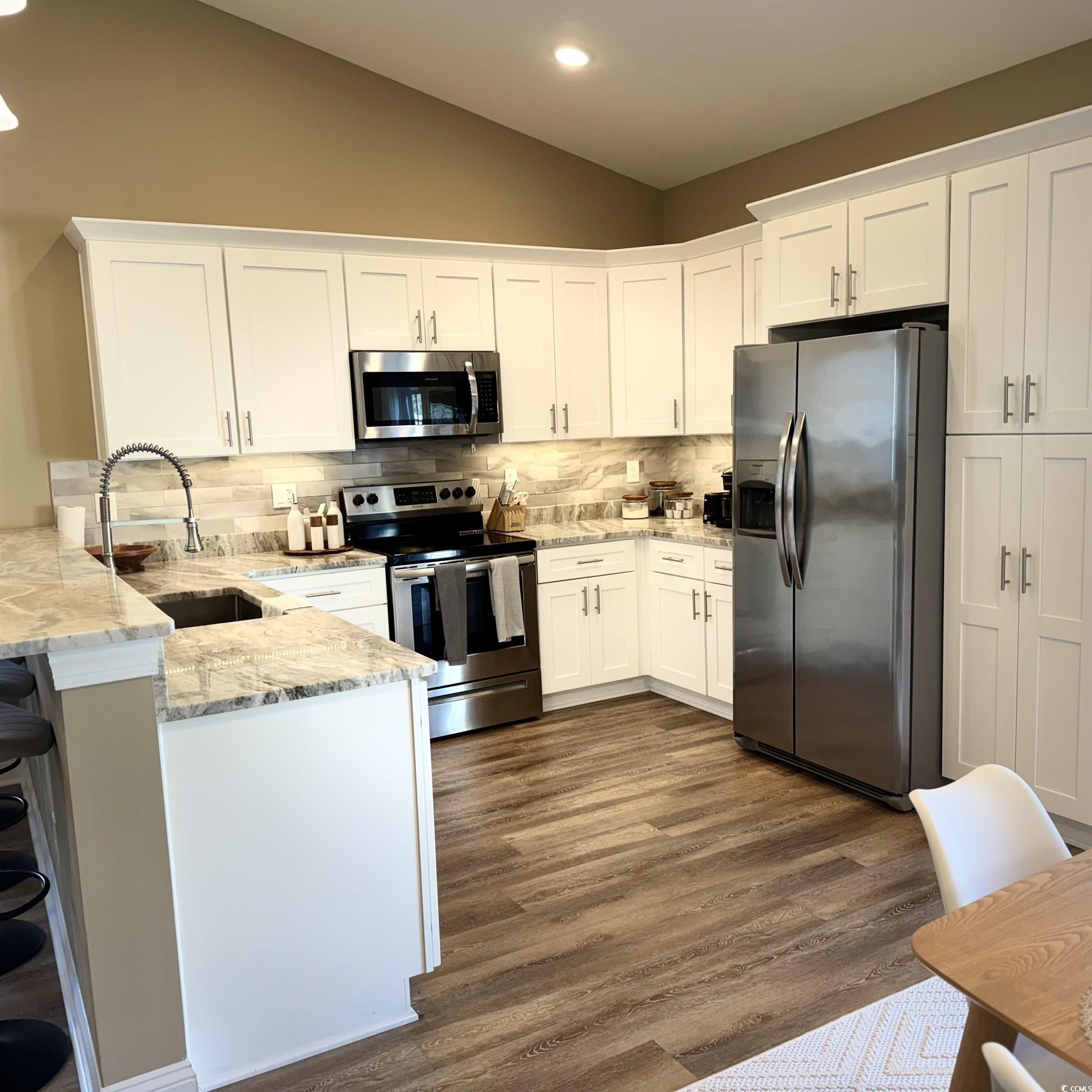 633 11th Avenue South Myrtle Beach, SC 29577 - Photo 7 of 25 Kitchen with stainless steel appliances, white cabinetry, light stone counters, tasteful backsplash, and vaulted ceiling