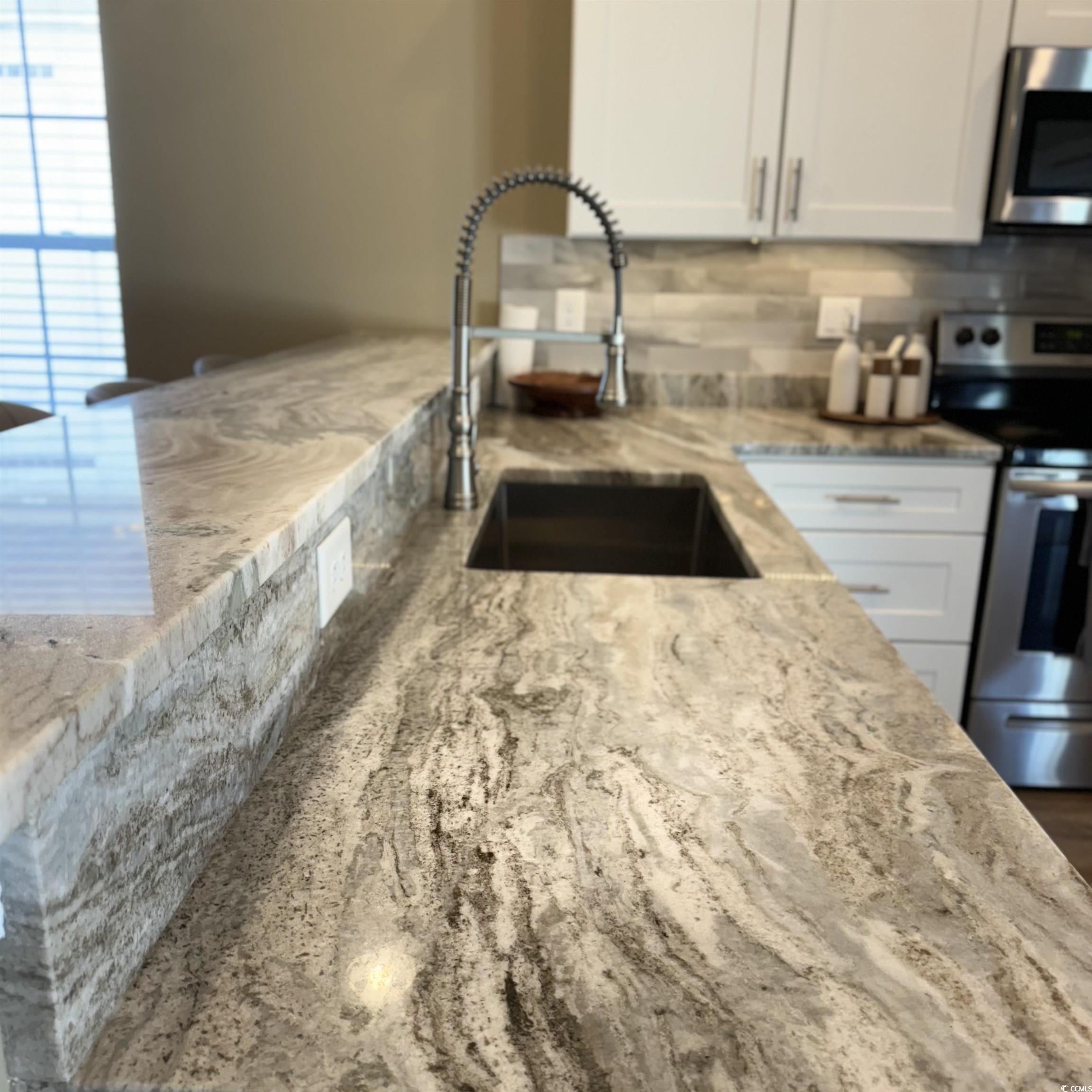 633 11th Avenue South Myrtle Beach, SC 29577 - Photo 8 of 25 Kitchen featuring appliances with stainless steel finishes, tasteful backsplash, white cabinetry, and light stone countertops