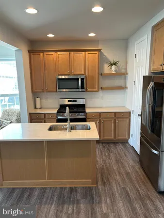 a kitchen with kitchen island granite countertop a stove a sink a refrigerator and cabinets