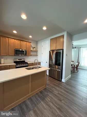a kitchen with stainless steel appliances granite countertop a stove a refrigerator a sink a oven with wooden floors and cabinets