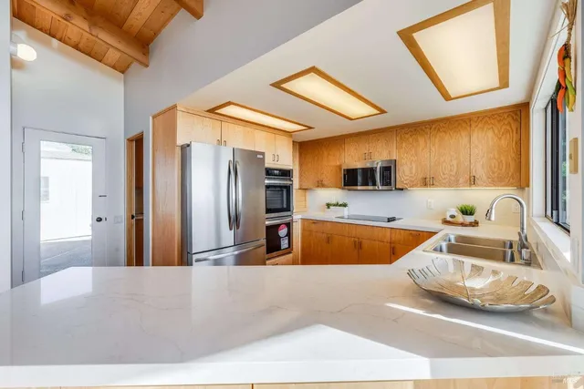 a kitchen with stainless steel appliances granite countertop a sink and a refrigerator