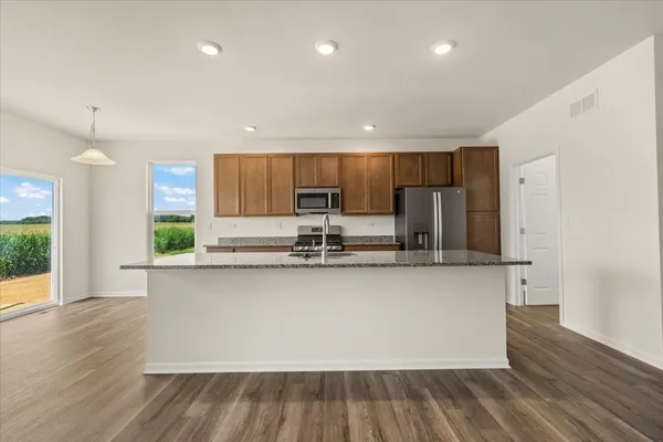 a kitchen with stainless steel appliances granite countertop a sink a stove a refrigerator and cabinets