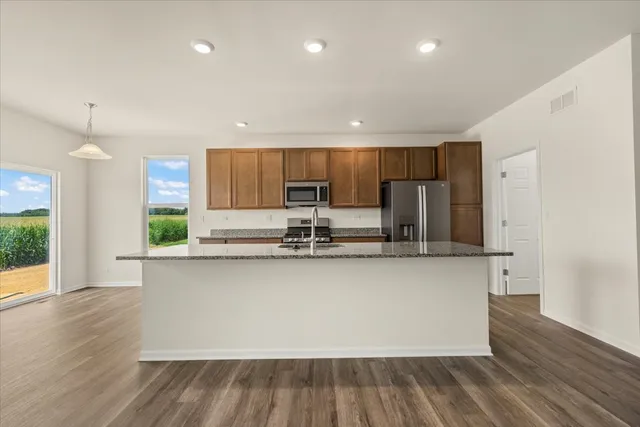 a kitchen with stainless steel appliances granite countertop a sink a stove a refrigerator and cabinets