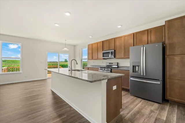 a kitchen with stainless steel appliances granite countertop a refrigerator a stove top oven a sink and dishwasher with wooden floor