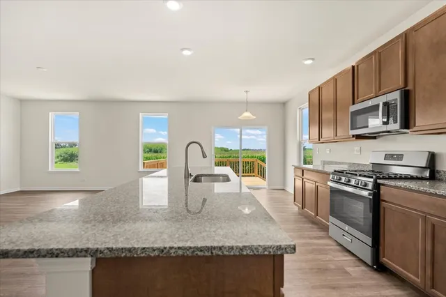 a kitchen with stainless steel appliances granite countertop a stove a sink and a microwave