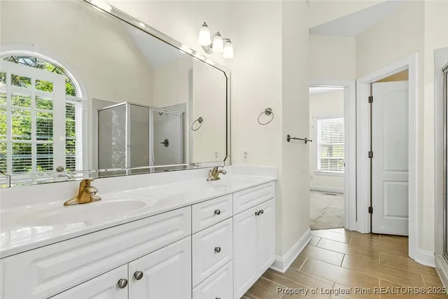 a spacious bathroom with a double vanity sink a mirror a bathtub and next to a window