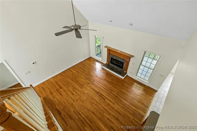 a view of an empty room with wooden floor and a ceiling fan