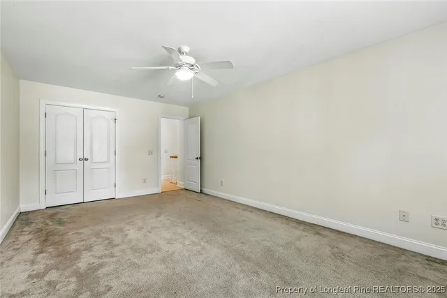 an empty room with a bathroom and fan