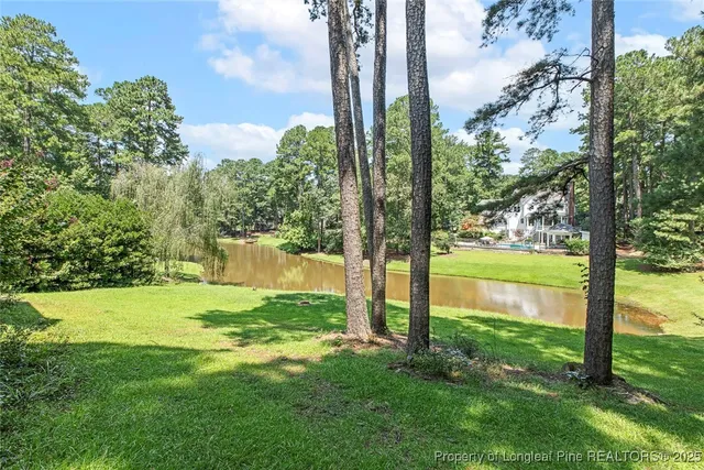 a view of a brick house with a big yard and large trees