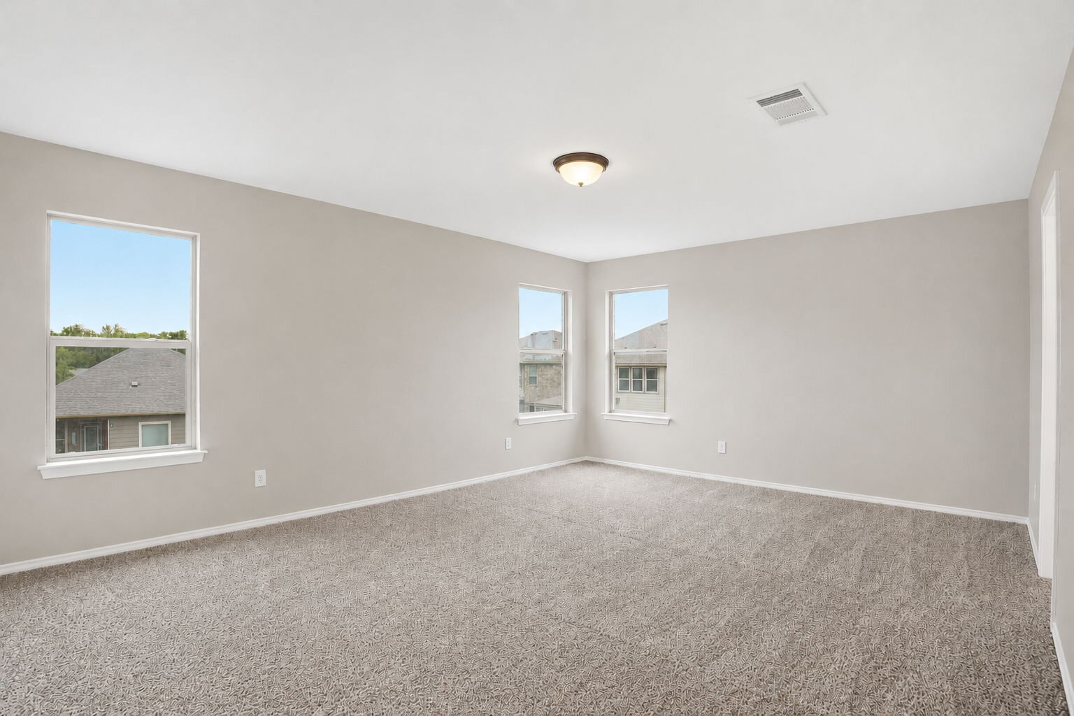 670 Landon Samuel Loop Pflugerville, TX 78660 - Photo 7 of 22 Spacious room with light gray carpeting, three windows, white trim, and a ceiling-mounted light fixture