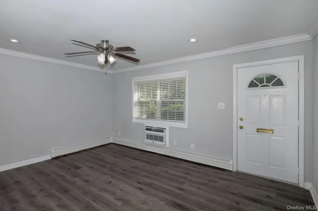 an empty room with wooden floor chandelier fan and windows