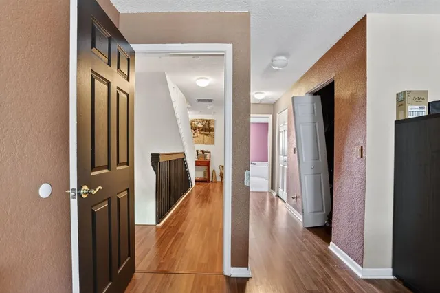 a view of a hallway with wooden floor and staircase