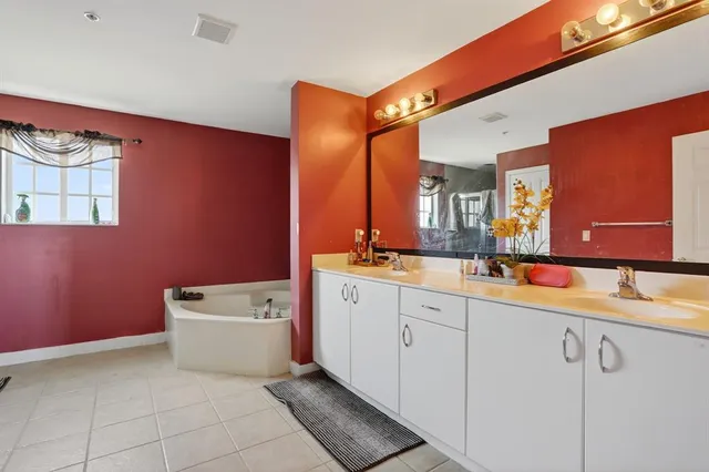 a bathroom with a double vanity sink mirror and bathtub