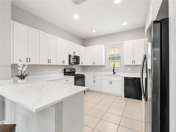 a kitchen with a sink a stove top oven and white stainless steel appliances