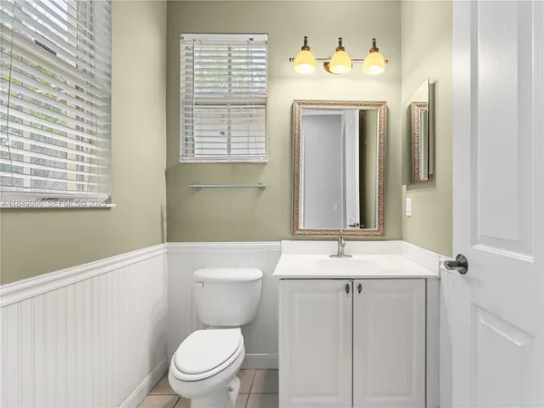a bathroom with a sink a mirror a toilet and a window