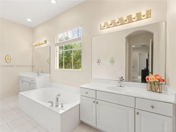 a bathroom with a double vanity sink mirror and bathtub