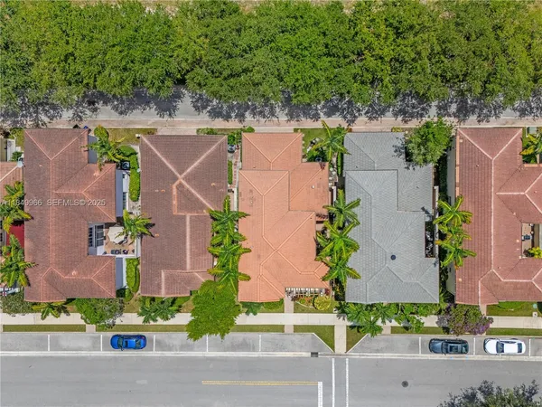 an aerial view of a house with a yard and couple of cars parked in front of it