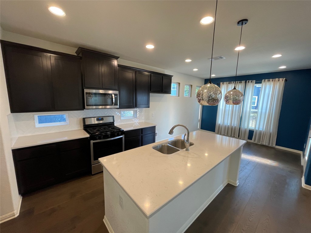 142 Simon Kyle, TX 78640 - Photo 2 of 16 a kitchen with stainless steel appliances a sink a stove a refrigerator and a microwave