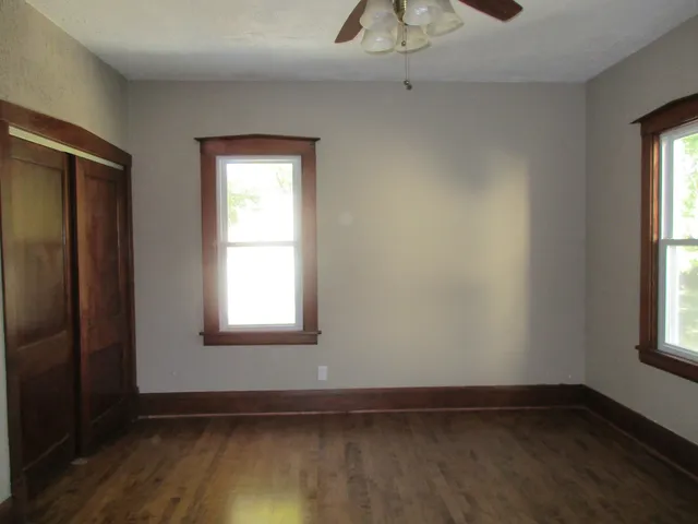 an empty room with wooden floor and windows