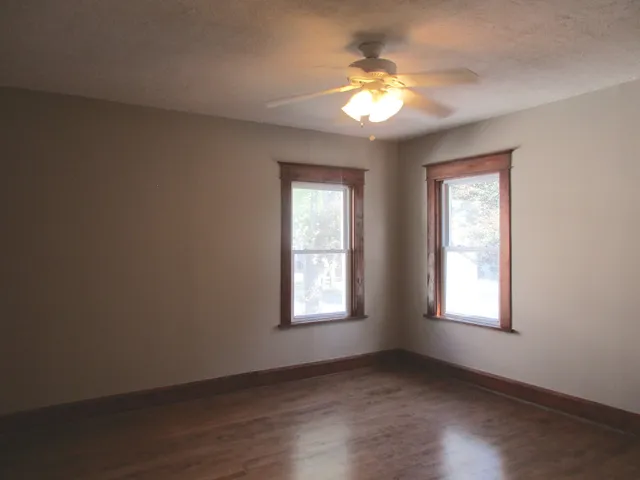 a view of an empty room with a window and wooden floor