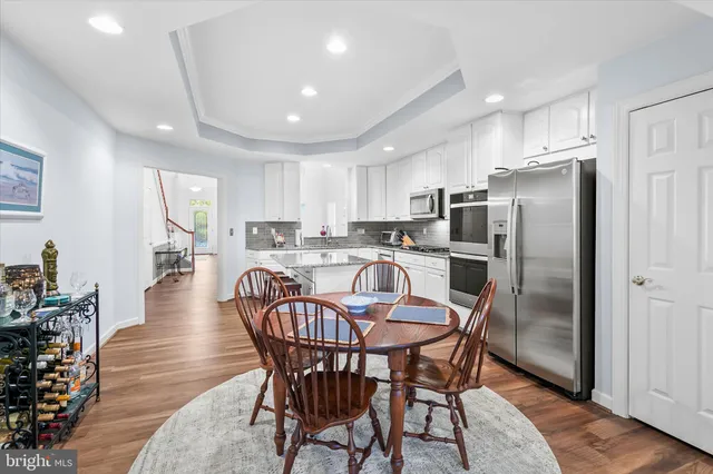 a kitchen with stainless steel appliances granite countertop a dining table chairs refrigerator and wooden cabinets
