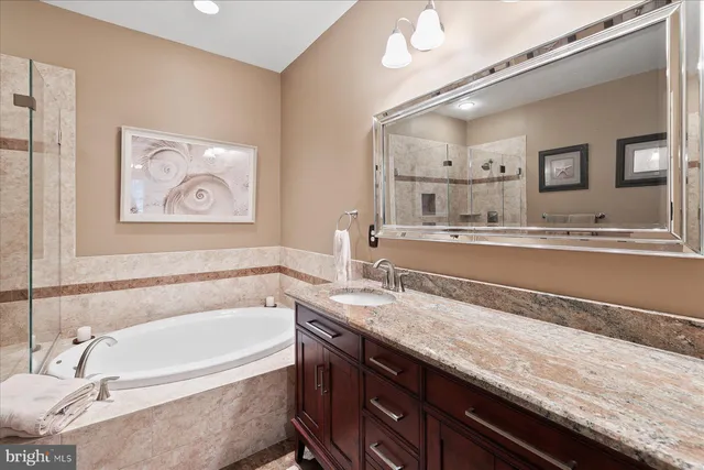 a spacious bathroom with a granite countertop sink mirror and bathtub