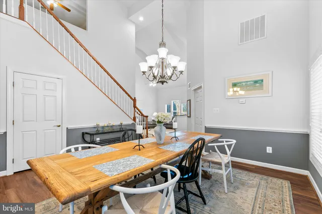 a dining room with wooden floor a chandelier a wooden table and chairs