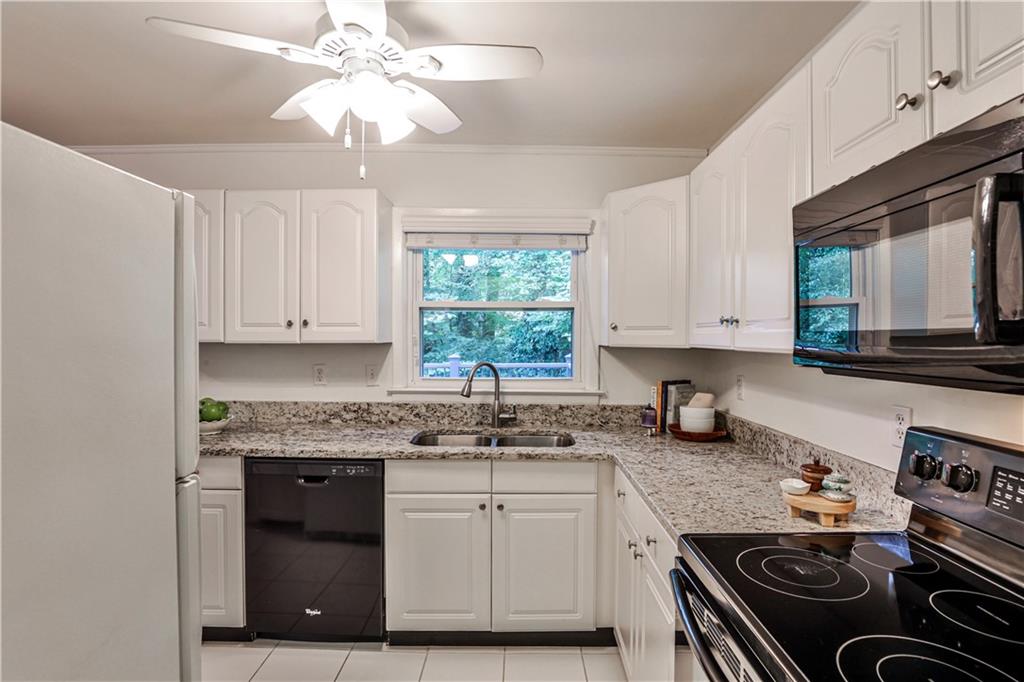 1010 Greenbriar Circle Decatur, GA 30033 - Photo 11 of 28 a kitchen with granite countertop a stove a sink and dishwasher with white cabinets