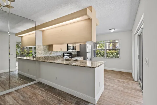 a kitchen with stainless steel appliances granite countertop a sink and a large window