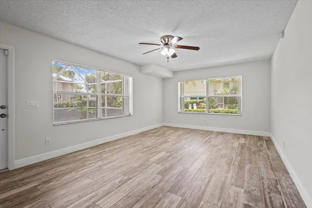 a view of an empty room with a window and wooden floor