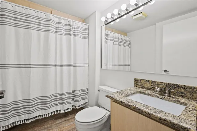 a bathroom with a granite countertop bathtub sink vanity mirror and toilet