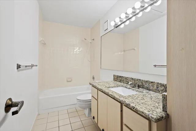 a bathroom with a granite countertop sink a toilet and shower