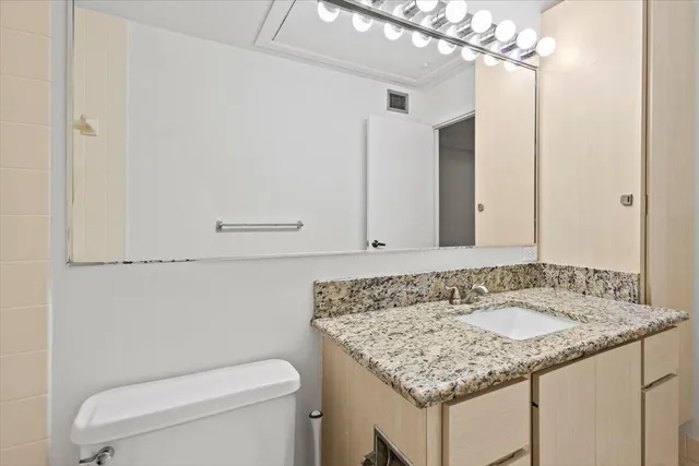 a bathroom with a granite countertop sink a toilet and a mirror
