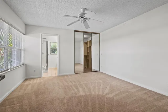 a view of a big room with windows and chandelier fan