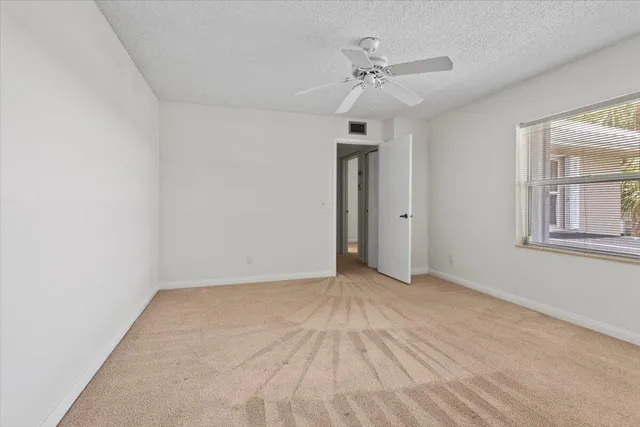 an empty room with a ceiling fan and a window