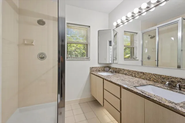 a bathroom with a granite countertop sink a mirror and shower