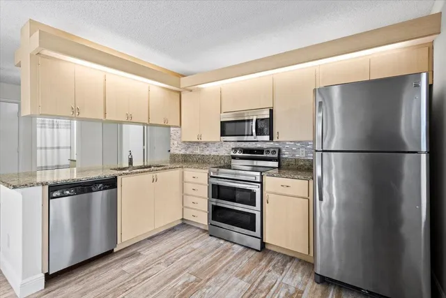 a kitchen with stainless steel appliances a refrigerator sink and microwave