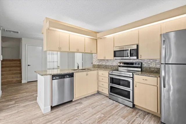 a kitchen with stainless steel appliances granite countertop a stove a sink and a refrigerator