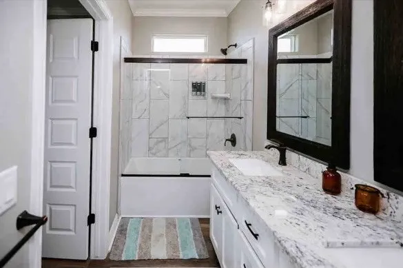a bathroom with a granite countertop sink a mirror and shower