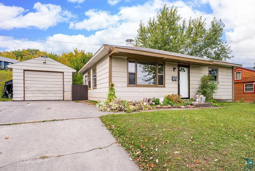 66 Banks Boulevard Silver Bay, MN 55614 - Photo 1 of 19 View of front facade with a front yard, an outbuilding, concrete driveway, and a detached garage