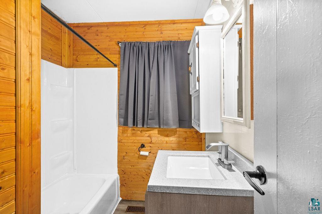 66 Banks Boulevard Silver Bay, MN 55614 - Photo 11 of 19 Bathroom featuring wood walls, vanity, and tub / shower combination