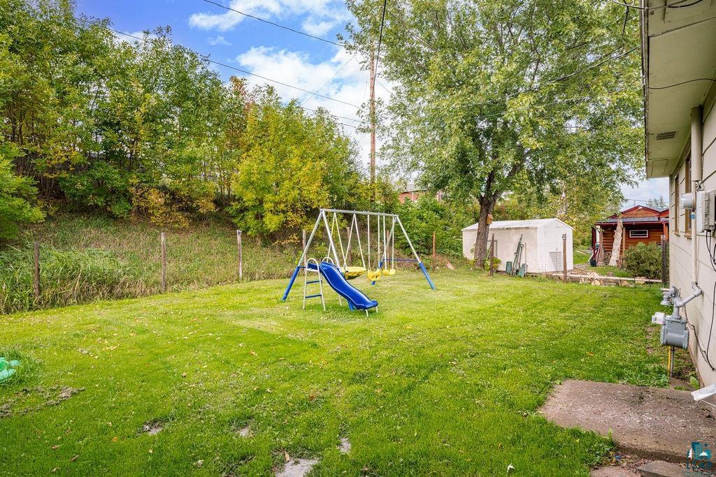 66 Banks Boulevard Silver Bay, MN 55614 - Photo 16 of 19 View of green lawn featuring a playground and a storage shed