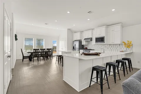 a kitchen with stainless steel appliances granite countertop a table and chairs in it