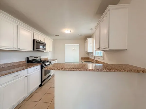 a large kitchen with granite countertop a sink and a stove
