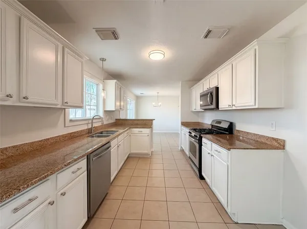 a large kitchen with stainless steel appliances granite countertop a sink and cabinets