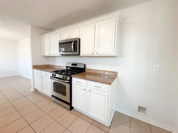 a kitchen with stainless steel appliances granite countertop a stove a sink and a microwave