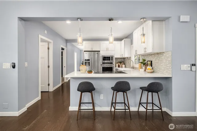 a kitchen with stainless steel appliances a table chairs refrigerator and sink
